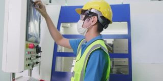 亚洲人工人，人们戴上防护口罩在生产工厂由于新冠疫情危机。男性工程师在工业中负责检查和操作机器。