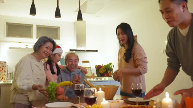 幸福的家庭时间和关系，亚洲大家庭有一个小聚会，一起在家里吃东西。爷爷很高兴看到他的孩子和侄子在家里的餐桌上吃饭，分享食物。