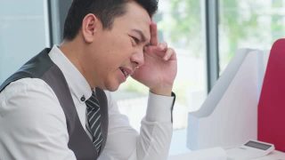 在办公室生病综合症，亚洲商人在电脑上工作有头痛，感到压力和生病的工作。商人对分配给他的工作感到灰心丧气。视频素材模板下载
