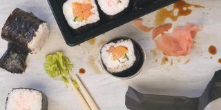 用筷子夹住寿司，放入酱油中。桌上乱糟糟的