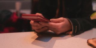 一名亚洲女性在露台咖啡馆使用智能手机