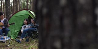 一群年轻的旅行者喜欢带着吉他在绿色森林露营