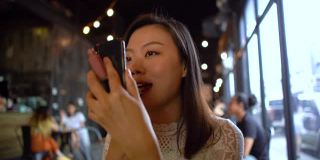 年轻的亚洲女性用智能手机涂口红
