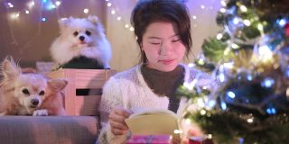 快乐圣诞节与亚洲女性休闲毛衣坐放松阅读小说书与小哈巴狗坐在一起与蛤和快乐的圣诞节日理念概念