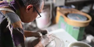 亚洲华人老人与老花泥塑艺术家在他的工作室与纺织陶瓷轮工作