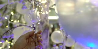 购物中心，一名男子正在触摸挂在树上的圣诞装饰品。节日气氛概念。