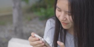 亚洲年轻女子边吃边玩手机。