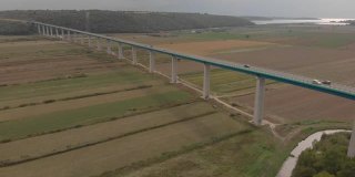 Flying over long Mirna bridge. Cars move on motorway over fields and river. Aerial of Croatia
