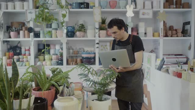 在他的植物精品店里用笔记本电脑工作的小企业主