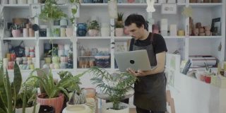 在他的植物精品店里用笔记本电脑工作的小企业主