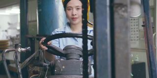 幸福微笑的亚洲女女工在安全帽驾驶叉车在仓库工厂
