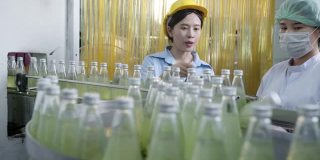 亚洲女主管在饮料加工厂检查药草饮料生产线。女工检查瓶中饮料产品流水线加工厂工业理念