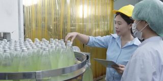亚洲女主管在饮料加工厂检查药草饮料生产线。女工检查瓶中饮料产品流水线加工厂工业理念