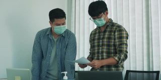 在病毒爆发期间，两名员工戴着口罩，共同分析公司的财务报表。