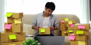 man在线企业家使用胶带打包包裹盒子在家里的办公室，准备产品交付给客户，(中小企业)