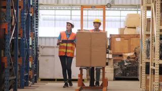 亚洲女经理拿着剪贴板检查清单存货和工人使用手堆垛机一起走在仓库。视频素材模板下载