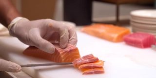 4K超高清慢动作手持:拉近厨师的手切生鲑鱼作为生鱼片，日本美食。