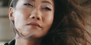 一个美丽的亚洲女人的特写肖像与风吹过她的头发
