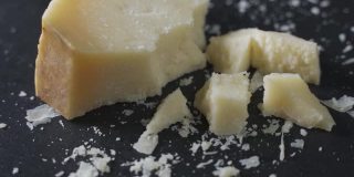 硬邦邦的帕尔玛干酪放在黑色的石头盘子里。板旋转,特写