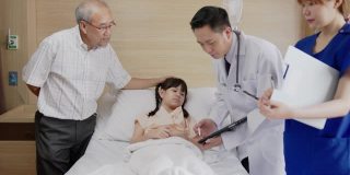 亚洲友好的医生男子与父母交谈，并显示x光结果平板电脑在病房。儿童医院儿科病房。医生跟进病情病人。
