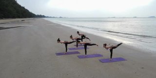 鸟瞰图的团队身体战斗群做瑜伽在一个阳光灿烂的一天在海滩上。