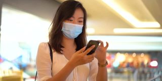 年轻的亚洲妇女戴着防护口罩和网上购物