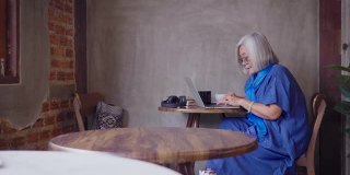 亚洲资深女性工作与笔记本电脑，而坐在咖啡厅咖啡厅，人们的生活方式技术概念