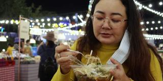 4K，亚洲女孩吃泰国街头食物叫yum米粉木托盘在夜市的人走