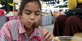 4K，亚洲女孩吃泰国街头食物叫猪肉烤木托盘在夜市的人走