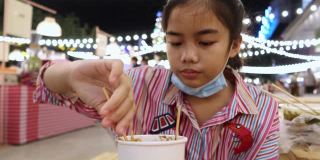 4K，亚洲女孩吃泰国街头食物叫Isan火锅与猪肉在夜市在人们走