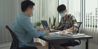 Asian colleagues are working in the office while wearing masks during the outbreak of the virus.