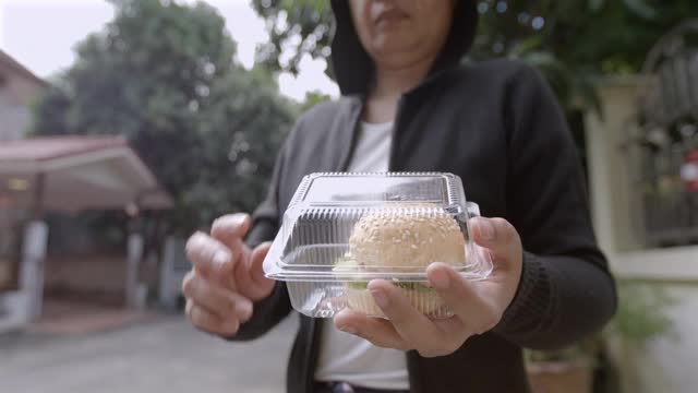 女人吃塑料盒子里的汉堡包慢镜头