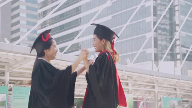 两名应届毕业生在毕业典礼上互相拥抱，表达他们的喜悦。