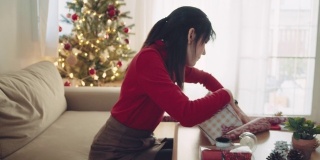 年轻女子在圣诞节期间在家包装圣诞礼物。