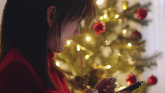 一个亚洲女孩在圣诞节用智能手机网购