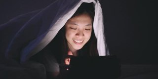 亚洲大学生青少年社交媒体成瘾在家里放松使用数字平板电脑和智能手机，放松在社交网络上的网络游戏和短信在深夜的床上