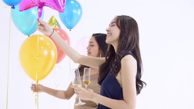 亚洲女子在白色背景气球的新年晚会上跳舞