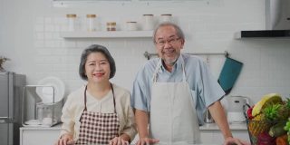 夫妇老亚洲长者幸福生活在家庭厨房。爷爷抱着奶奶幸福地笑着一起享受退休生活。老年人的家庭关系和活动概念。