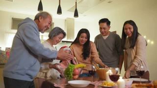 快乐的家庭时间和关系，亚洲大家庭有一个小的圣诞聚会，在家里一起吃食物。孩子很高兴看到父母、表兄准备食物并带到家里的餐桌上。视频素材模板下载