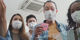 小组头脑风暴的亚洲人把便利贴贴在窗户上。团队合作的商务人士戴上口罩，可以防止新冠病毒感染，在办公室讨论和分享解决问题的想法。