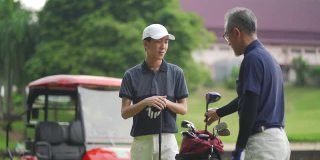 一位亚裔华人父亲在高尔夫球场教儿子打高尔夫球