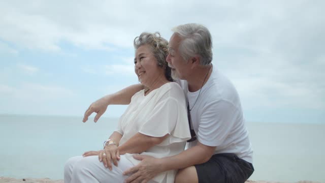 资深亚洲夫妇在海滩拥抱，4K DCI慢镜头