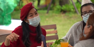 一名戴着外科口罩的女性一起在户外的咖啡厅放松，用智能手机自拍