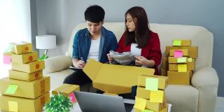 夫妇在线企业家检查和打包包裹盒子在家里的办公室，准备产品交付给客户，(中小企业)