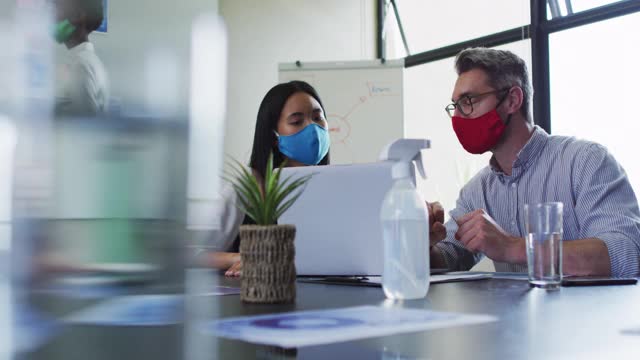 在现代办公室里，各式各样的男女同事戴着面具在手提电脑前讨论