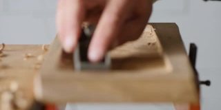 关闭了。木雕师用小刨子刨胡桃木板。工匠在做一个茶盘。vagatabon。乐器的声音