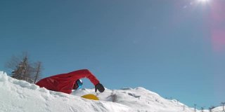 从下往上:当滑雪者在做滑雪特技时，雪花在阳光下闪闪发光。