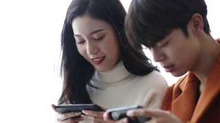 年轻的亚洲夫妇在玩手机视频素材模板下载