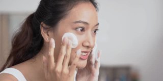 美丽的亚洲女性用水洗脸洗脸。