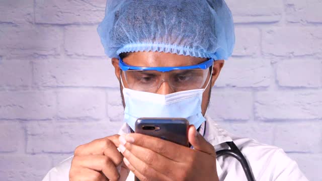 体贴的医生在使用智能手机面罩。